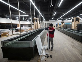 A worker assembles a fixture at a Sungiven Foods grocery store under construction at City Square shopping centre, in Vancouver, on Thursday October 24, 2019.