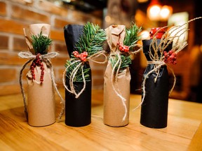 Four Christmas decorated bottles with ribbons and fir-tree branch on the wooden table on the background of brick wall. Getty stock photo. For 1214 salut gismondi list2 [PNG Merlin Archive]