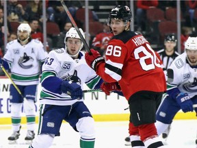 Quinn Hughes of the Vancouver Canucks, left, will aim to even the score with his brother Jack of the New Jersey Devils when the team meet Sunday afternoon at Rogers Arena.