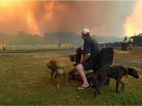 TOPSHOT - Locals watch as bushfires impact on farmland near the small town of Nana Glen, some 600kms north of Sydney on November 12, 2019. - Bushfires reached within kilometres (miles) of Sydney's city centre prompting firefighting planes to spray red retardant over trees and houses in a northern suburb. (Photo by WILLIAM WEST / AFP)