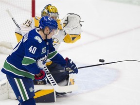 Elias Pettersson tries to tip the puck out of the air in front of Nashville Predators goalie Pekka Rinne.