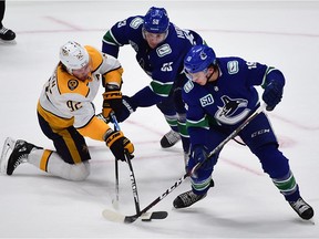 Nov 12, 2019; Vancouver, British Columbia, CAN; Nashville Predators forward Ryan Johansen (92) reaches for the puck against Vancouver Canucks forward Bo Horvat (53) and forward Jake Virtanen (18) during the third period at Rogers Arena. Mandatory Credit: Anne-Marie Sorvin-USA TODAY Sports