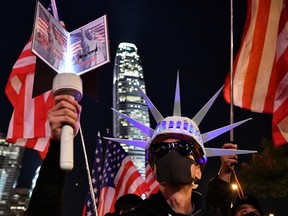A participant holds a torch and wears headgear modelled after the Statue of Liberty as people assemble for a gathering of thanks at Edinburgh Place in Hong Kong's Central district on November 28, 2019, after U.S. President Donald Trump signed legislation requiring an annual review of freedoms in Hong Kong.
