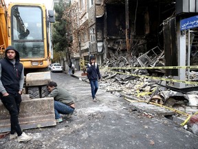 People walk near a burnt bank, after protests against increased fuel prices, in Tehran, Iran November 20, 2019.