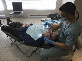 UBC School of Dentistry hygiene student Timothy Supan treats patient Dwight Harvey during a free dental clinic run by the Union Gospel Mission at The Orchard townhouse complex in Surrey on Nov. 20.