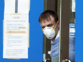 A staff member at York Central hospital in Richmond Hill, Ont., glances out the doors of the closed facility after fears the 2003 SARS outbreak was spreading further. At its peak, the outbreak caused people to avoid human contact, one epidemiology professor says.