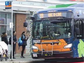 Transit users wait to board the 99B Line bus at Commercial and Broadway streets in Vancouver on Nov. 15.