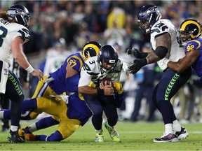 LOS ANGELES, CALIFORNIA - DECEMBER 08: Quarterback Russell Wilson #3 of the Seattle Seahawks is sacked by defensive end Morgan Fox #97 of the Los Angeles Rams  during the game at Los Angeles Memorial Coliseum on December 08, 2019 in Los Angeles, California.