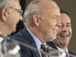 Alberta Premier Jason Kenney, right, looks on as B.C. Premier John Horgan, centre, speaks at The Council of Federation provincial and territorial premiers meeting at Mississauga's Hilton Toronto Airport on Dec. 2. At left is New Brunswick Premier Blaine Higgs.