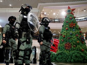 Riot police stand guard next to a Christmas tree inside a shopping mall during an anti-government protest on Christmas Eve at Tsim Sha Tsui in Hong Kong, China, December 24, 2019.