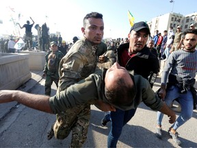 A wounded member of Hashd al-Shaabi (paramilitary forces) gets help during a protest to condemn air strikes on their bases, outside the main gate of the U.S. Embassy in Baghdad.