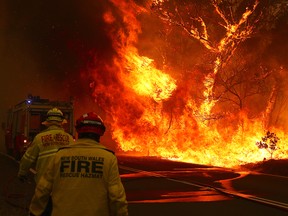 Firefighters run to move their truck as a bushfire burns next to a major road and homes on the outskirts of the town of Bilpin on December 19, 2019 in Sydney, Australia. (David Gray/Getty Images)