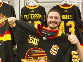 Spencer Samson, retail assistant manager at the Canucks Team Store in Rogers Arena, holds a Bo Horvat No. 53 jersey, the colours and design worn by the team that went to the 1994 Stanley Cup final.