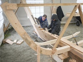 Metis carver Patrick Calihou (in plaid) and Sean Anton (in dark hoodie) construct a traditional York boat, built with plans sourced from Ft. Garry, at the Fort Langley National Historic Site.