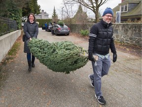 Mark Pickup and Eline De Rooij walk their tree to the car at Aunt Leah's Christmas tree lot in Vancouver, BC, December 1, 2019. Some Christmas tree growers in BC are reporting a shortage of Christmas trees, which is being felt across North America.