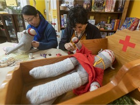 A stuffed animal lays in the triage crib while Susan Ouyang (left) and Surya Govender sew and mend a stuffed animal while at The Vancouver Learnary Society.