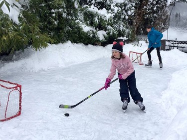 Siblings Blythe, 8, and Drew Timlin, 15, take advantage of Wednesday's snow day with a game of shinny on their miniature backyard rink in North Vancouver.  [PNG Merlin Archive]