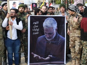 Member of Syria's military gather in the central Saadallah al-Jabiri square in the northern Syrian city of Aleppo on January 7, 2020, to mourn and condemn the death of Iranian military commander Qasem Soleimani (portrait), and nine others in a U.S. air strike in Baghdad.