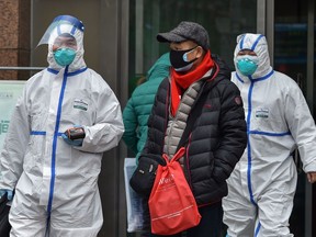 Medical staff wearing clothing to protect against a previously unknown virus walk outside a hospital in Wuhan on January 26, 2020, a city at the epicentre of a viral outbreak that has killed at least 56 people and infected nearly 2,000. - China on January 26 expanded drastic travel restrictions to contain the viral contagion, as the United States and France prepared to evacuate their citizens from the quarantined city at the outbreak's epicentre.