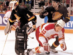 Vancouver Canucks netminder Kirk McLean battles with Calgary Flames forward Gary Roberts, falling. At right of McLean is Canucks defenceman Jeff Brown.