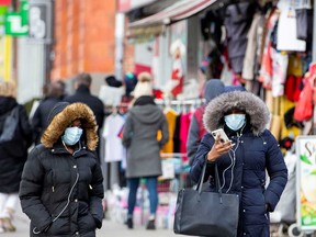 Pedestrians wear masks in downtown Toronto after three patients with novel coronavirus were reported in Canada.