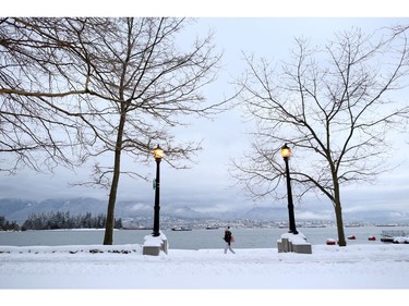 A woman walks along the seawall near Coal Harbour, with North Vancouver in the background, after a snow storm in downtown Vancouver, British Columbia, Canada January 15, 2020. REUTERS/Jesse Winter