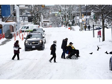 Pedestrians help a man who uses a wheelchair cross the street after a snow storm in downtown Vancouver, British Columbia, Canada January 15, 2020. REUTERS/Jesse Winter