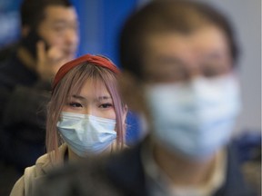 Passengers wear masks as they arrive at the international arrivals area at the Vancouver International Airport in Richmond, B.C., Thursday, January 23, 2020.