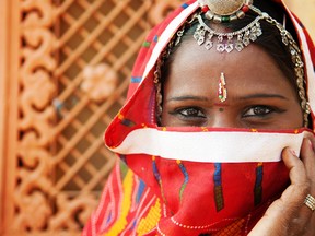 An Indian woman in a traditional sari, covering her face with a veil.