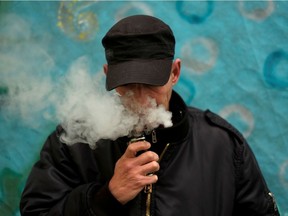 A man poses for a picture as he vapes.