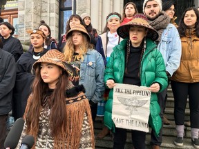 Ta'Kaiya, front, and Sii-am Hamilton, holding a sign, are seen standing with Indigenous youth demonstrating support for the Wet'suwet'en hereditary chiefs in northwest B.C. opposing the LNG pipeline project, in front of the B.C. legislature in Victoria on Friday, Jan. 24, 2020.