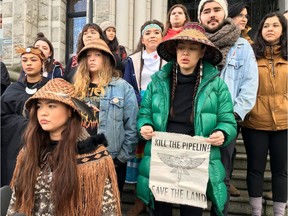 Ta'Kaiya, front, and Sii-am Hamilton, holding a sign, are seen standing with Indigenous youth demonstrating support for the Wet'suwet'en hereditary chiefs in northwest B.C. opposing the LNG pipeline project, in front of the B.C. legislature in Victoria on Friday, Jan. 24, 2020.