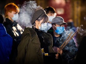 Incense burns as people wear face masks while marking the Lunar New Year at the International Buddhist Temple in Richmond late Friday.