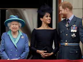 Britain's Queen Elizabeth II, and Meghan the Duchess of Sussex and Prince Harry watch a flypast of Royal Air Force aircraft pass over Buckingham Palace in London on Tuesday, July 10, 2018. Queen agrees to let Harry and Meghan move part-time to Canada after 'constructive' royal summit. She says she would have preferred Harry and Meghan to remain full-time royals but respects wish for an independent life.
