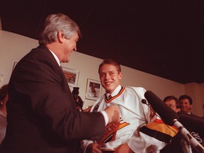 Pavel Bure puts on a Vancouver Canucks jersey for the first time on Nov. 1, 1991, while Canucks president and GM Pat Quinn looks on in delight.