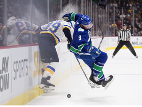 Vancouver Canucks' J.T. Miller, right, loses his footing while vying for the puck against St. Louis Blues' Ivan Barbashev during the first period.