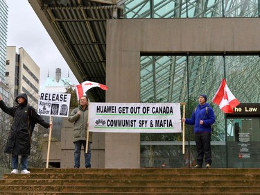 Steven Song (L), Shengwu Zhu and Zhiyuan Wang (R) hold signs outside of B.C. Supreme Court during Huawei Chief Financial Officer Meng Wanzhou's extradition hearing in Vancouver, British Columbia, Canada January 21, 2020.  REUTERS/Jennifer Gauthier