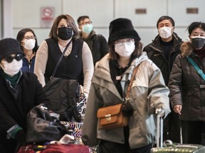 Passengers wear protective masks as they arrive at Beijing Capital Airport on Jan. 30, 2020.