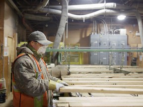 Feeding the production line, an equipment operator at C&C Wood Products checks over raw lumber flowing into the plant’s machinery on its way to becoming specialty wall paneling and trim for the North American home finishing market.