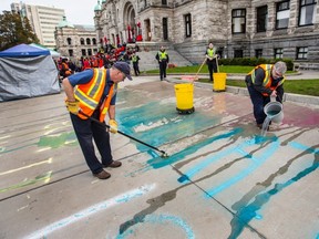 Workers clean Wet'suwet'en supporter chalk graffiti in front of the B.C. on Thursday.
Photograph