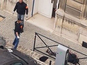 A picture obtained on October 5, 2019 shows two police members past the body of Mickael Harpon, 45-year-old computer expert, shot dead by a policeman after he stabbed four colleagues to death in a frenzied attack at Paris police headquarters in Paris on October 3, 2019.
