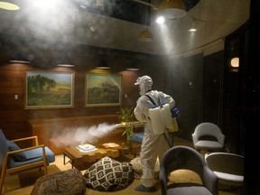 A worker wearing a protective suit uses a fogging machine to disinfect a business establishment in Shanghai on Feb. 9, 2020.