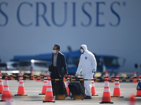A passenger disembarks from the Diamond Princess cruise ship - in quarantine due to fears of the new COVID-19 coronavirus - at the Daikoku Pier Cruise Terminal in Yokohama on February 19, 2020.