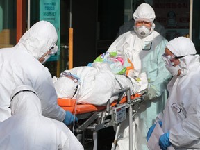 Medical workers wearing protective gear transfer a suspected coronavirus patient to another hospital from Daenam Hospital in Cheongdo county near the southeastern city of Daegu on Feb. 21, 2020.