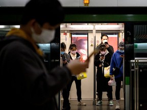TOPSHOT - People wearing protective facemasks use their mobile phones on the subway in Shanghai on February 25, 2020. - The new coronavirus has peaked in China but could still grow into a pandemic, the World Health Organization warned, as infections mushroom in other countries. (Photo by NOEL CELIS / AFP)