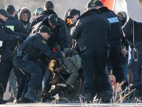 Police officers make an arrest during a raid on a Tyendinaga Mohawk Territory camp next to a blockaded railway crossing in Tyendinaga, Ont., on February 24, 2020.