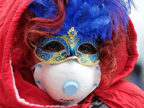 Masked carnival reveller wears protective face mask at Venice Carnival, which the last two days of, as well as Sunday night's festivities, have been cancelled because of an outbreak of coronavirus, in Venice, Italy February 23, 2020.
