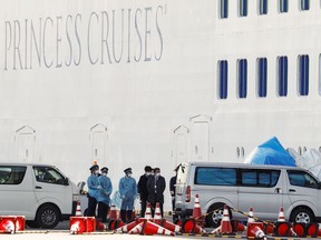 People wearing masks stand near the cruise ship Diamond Princess, where 10 more passengers tested positive for coronavirus, after it arrived at Daikoku Pier Cruise Terminal in Yokohama, south of Tokyo on Feb. 6.