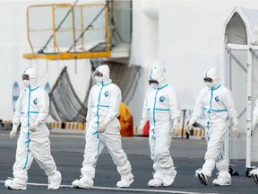 Workers wearing protective suits walk away from the quarantine cruise ship Diamond Princess south of Tokyo, Feb. 10.