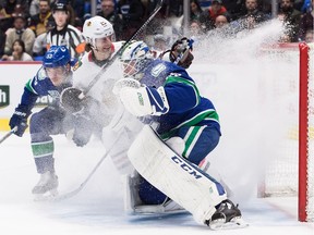 Vancouver Canucks' Bo Horvat, back left, and Chicago Blackhawks' Brandon Saad send snow flying as they come to a stop near Vancouver goalie Jacob Markstrom.